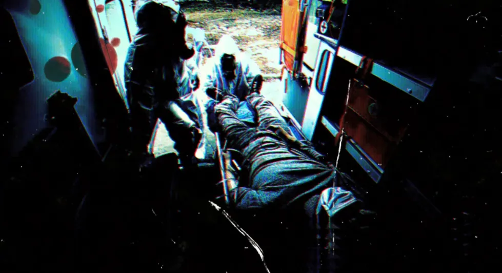 people in biohazard suits loading a man into an ambulance